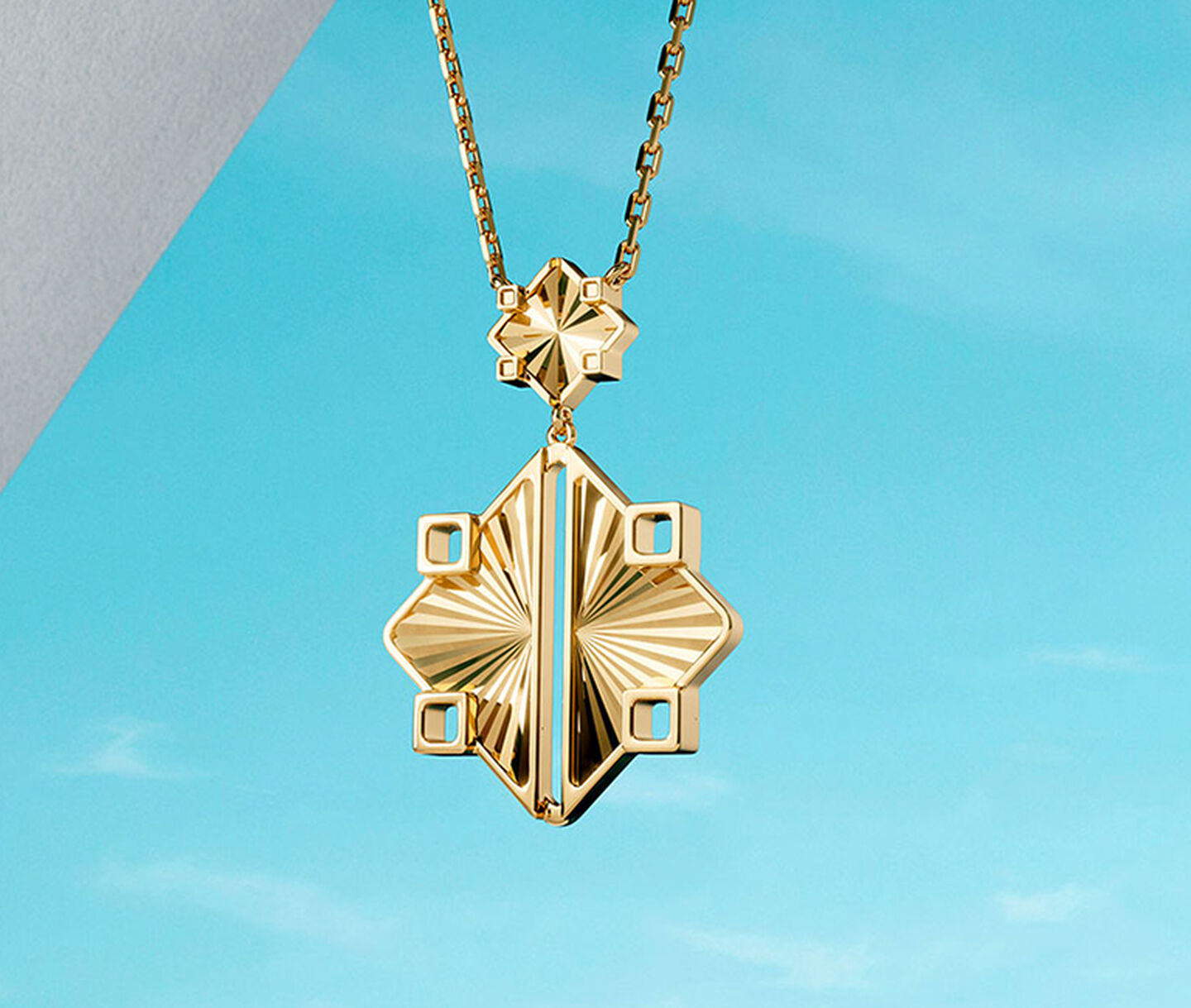 Birks Muse yellow gold drop necklace on a blue background.